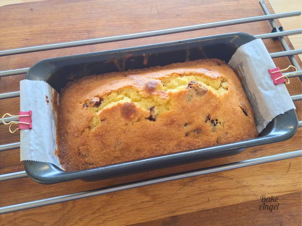 Fresh from the oven: dairy-free cranberry lemon loaf cake baked in a loaf pan, on a cooling rack.