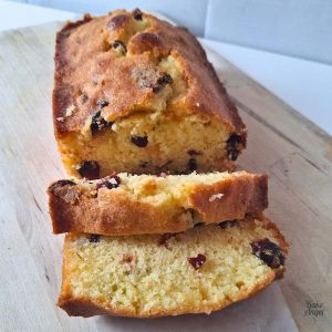 Dairy-Free Lemon Cranberry Loaf cake, sliced on a wooden board.