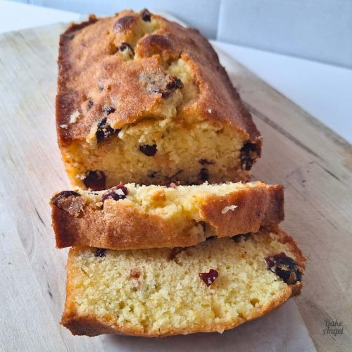 Dairy-Free Lemon Cranberry Loaf cake, sliced on a wooden board.