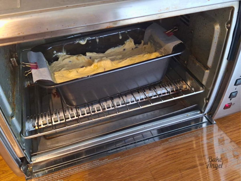 A pan of dairy-free lemon cranberry loaf cake in a countertop toaster oven, about to be baked.