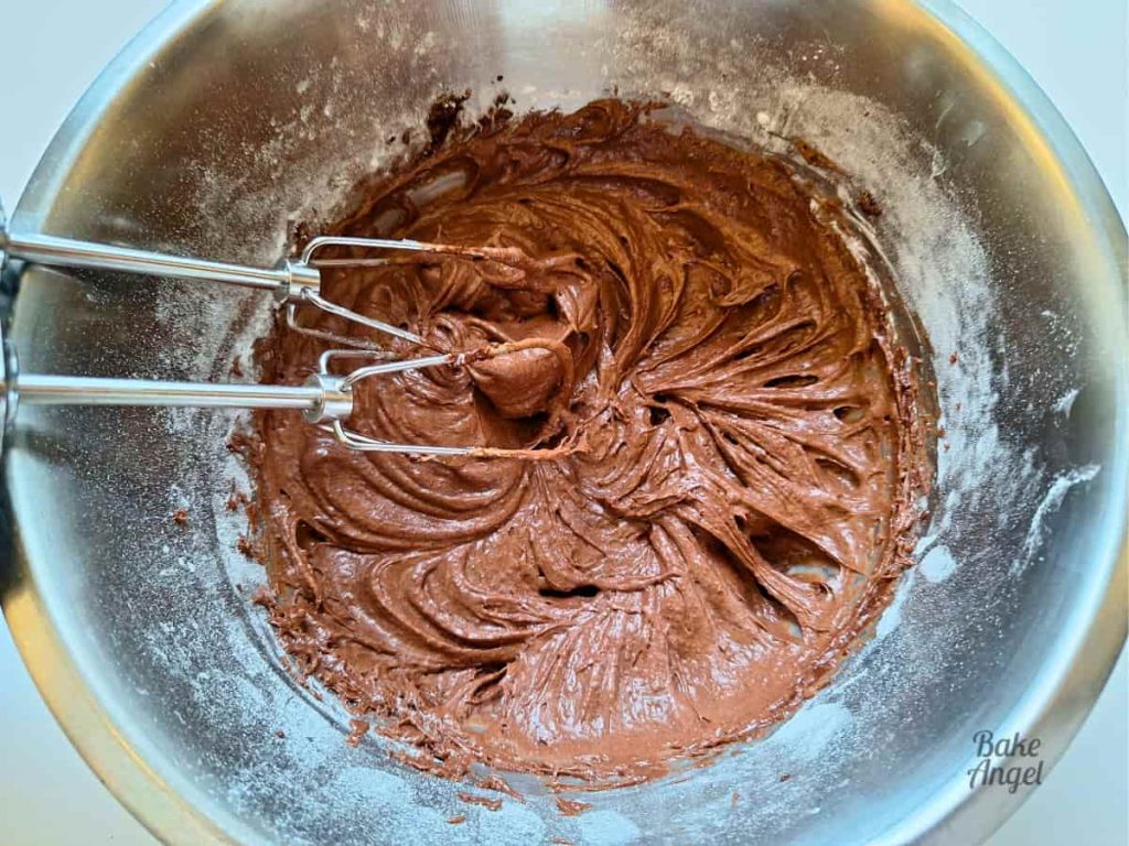 A bowl of freshly mixed dairy free chocolate cupcake batter with two whisk attachments in the bowl.