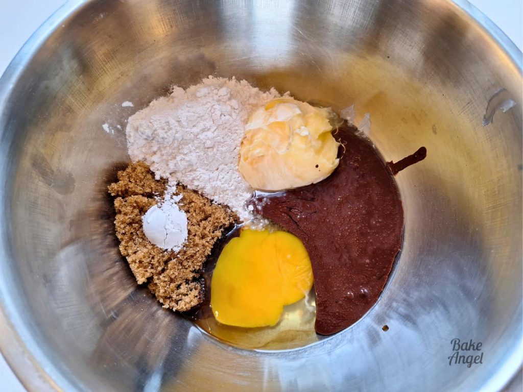 Small batch chocolate cupcake ingredients in a silver mixing bowl before combining.