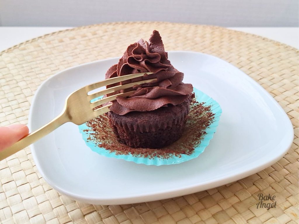 Close up of a gold fork about to slice a dairy free chocolate cupcake..