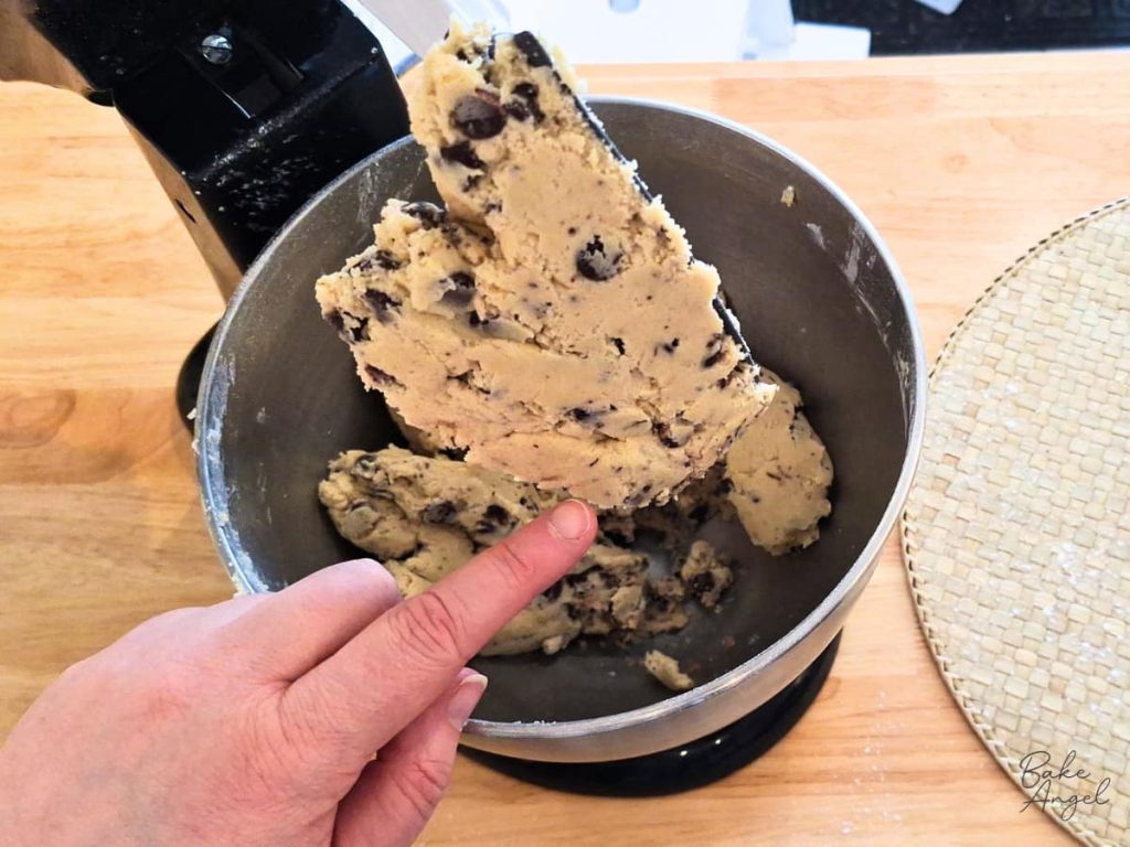 Thick chocolate chip cookie cake dough in stand mixer showing correct consistency