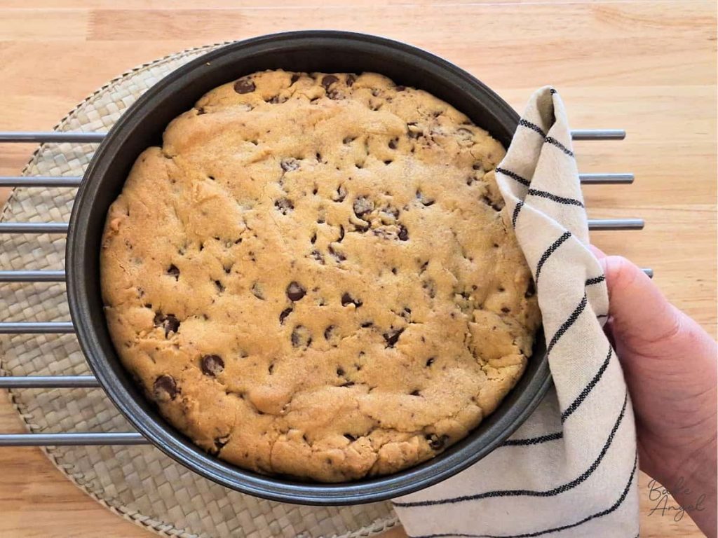 A baked cookie cake in a pan removed from the oven.