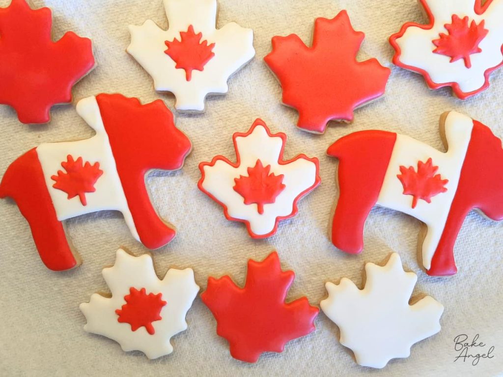 A set of decorated Canada Day sugar cookies in red and white royal icing.