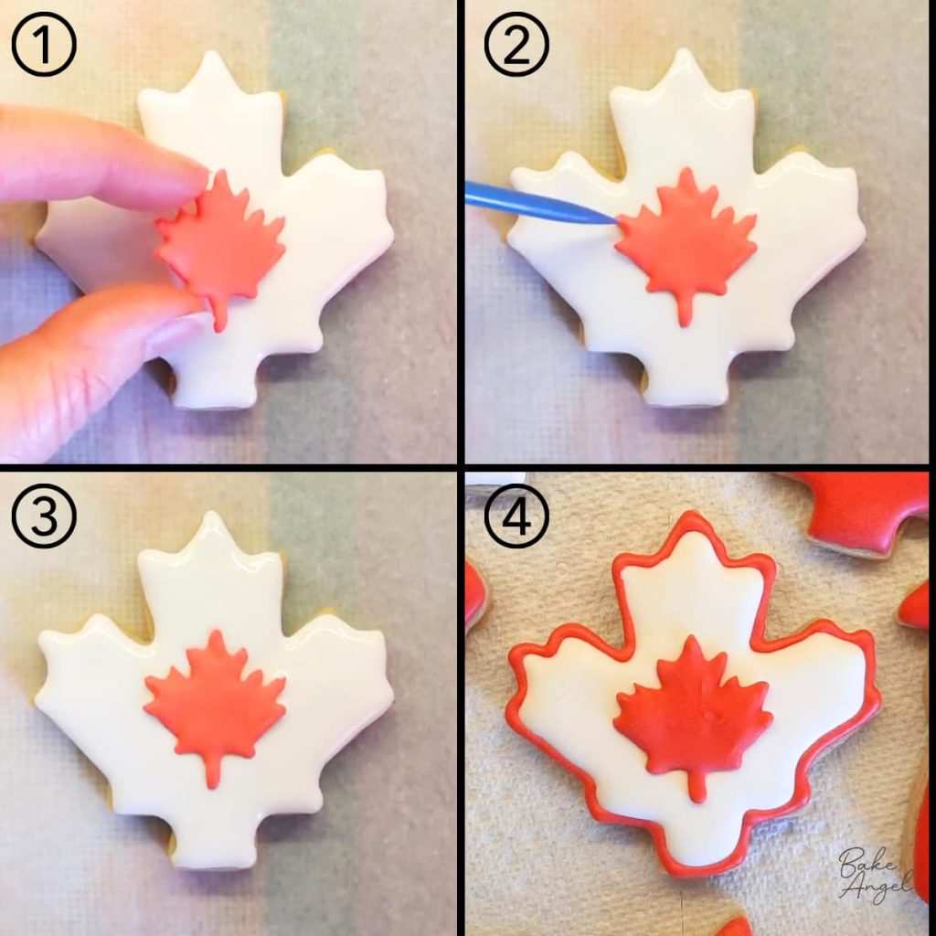 Adding a red maple leaf royal icing transfer to a white flooded sugar cookie.