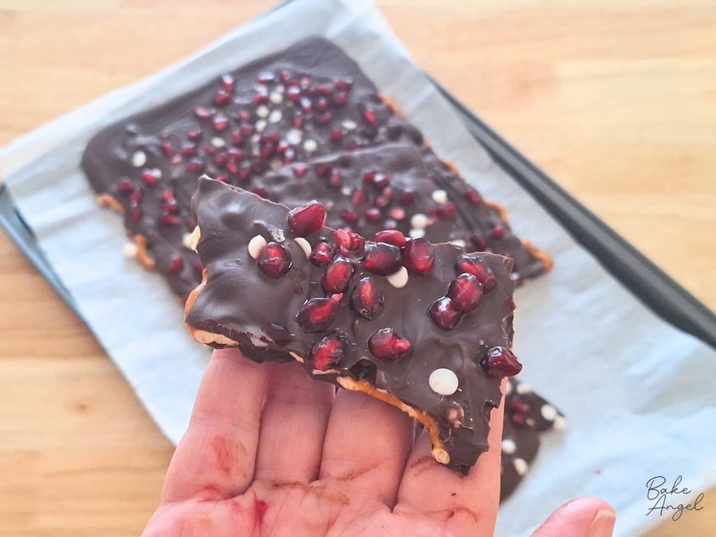 Holding a piece of vegan pomegranate pretzel bark.
