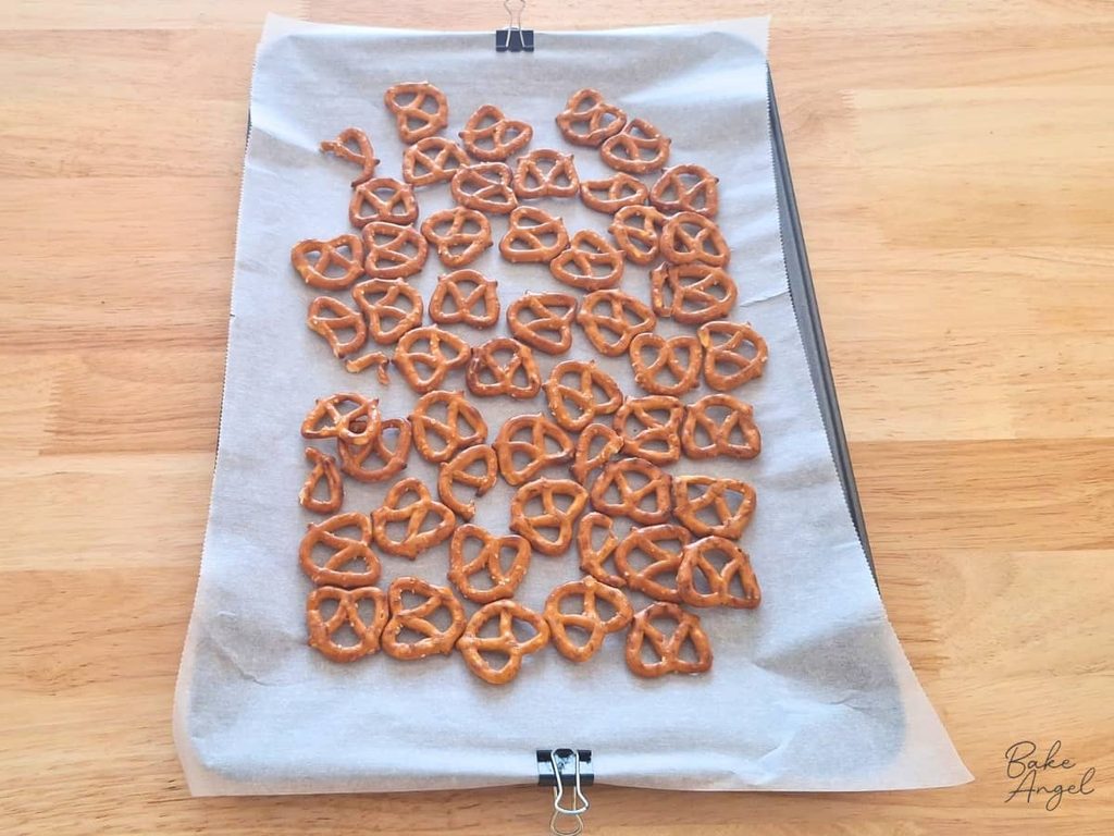 Pretzels laid out on a parchment lined baking tray for making pomegranate bark.