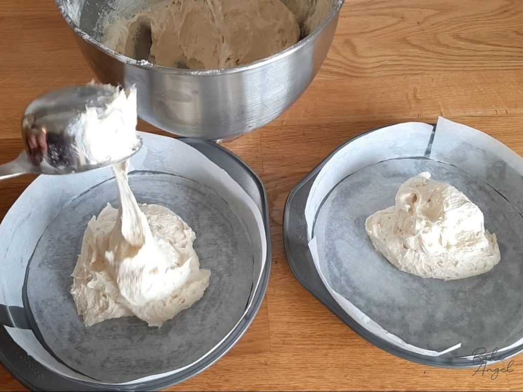 Victoria sponge cake batter being measured into two round cake pans.