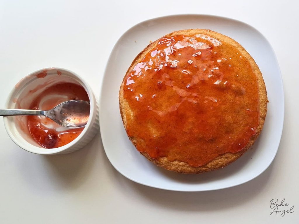 Strawberry jam spread on a layer of Victoria sponge cake.