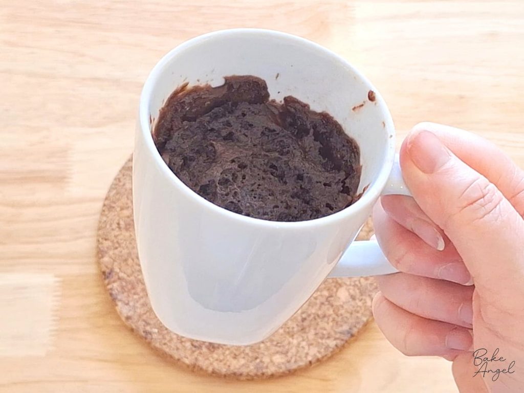 Chocolate mug cake freshly cooked in the microwave, risen inside a mug.