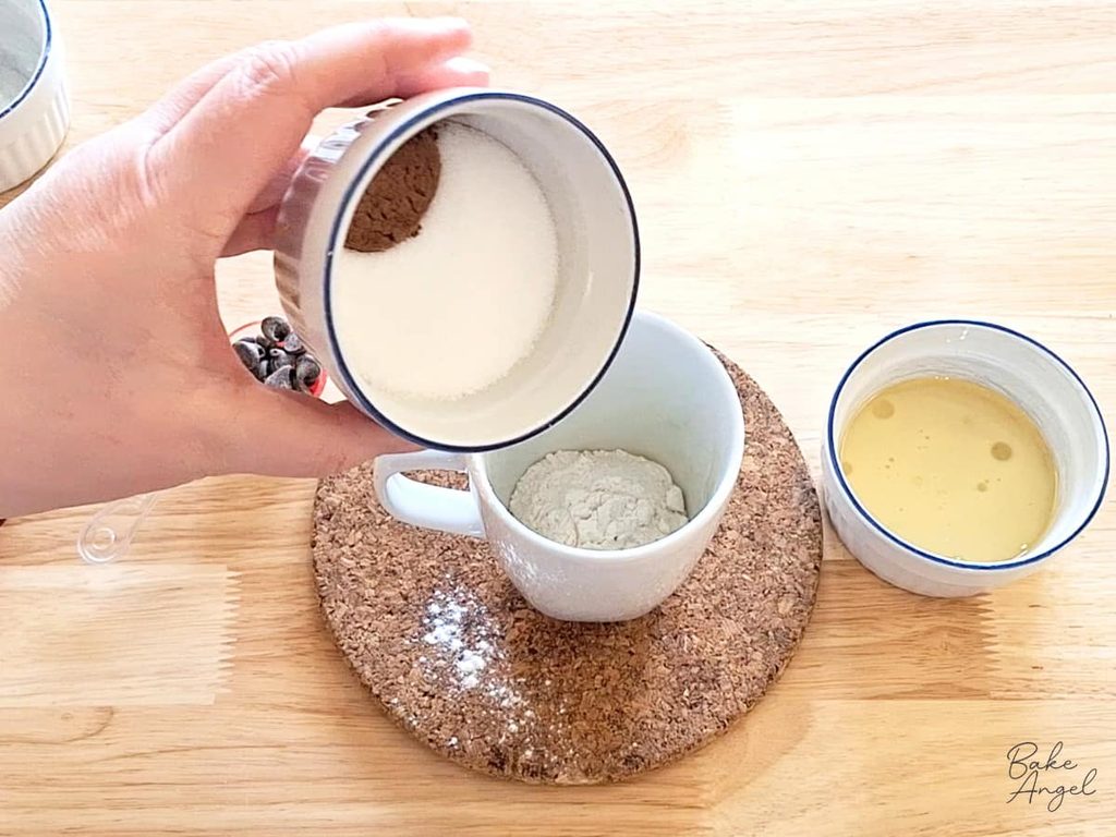 Flour, cocoa powder, sugar, baking powder and salt mixed together in a mug for chocolate cake.