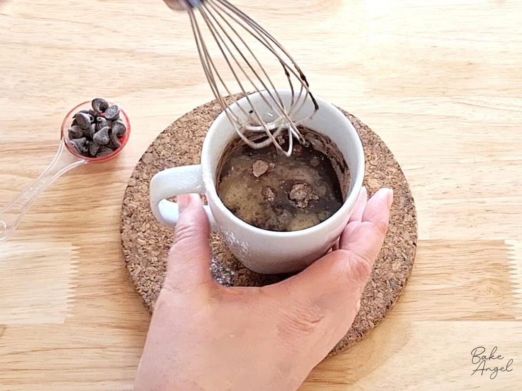 Chocolate mug cake batter being stirred together in a microwave-safe mug.