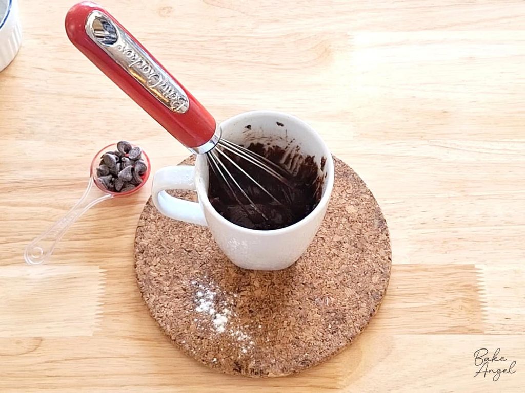 Thick chocolate cake batter mixed in a mug before adding chocolate chips.