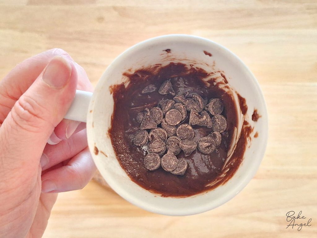 Chocolate chips sprinkled over the batter before microwaving the chocolate mug cake.
