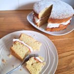 A slice of dairy-free gluten-free Victoria sponge cake on a plate, next to the whole cake.