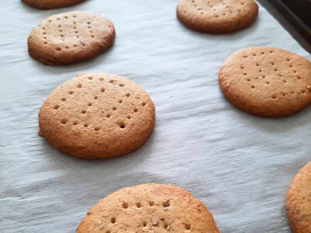 Side view of baked digestive biscuits on a baking tray.