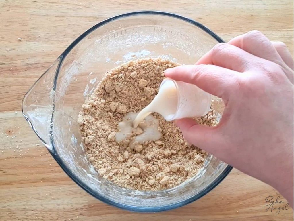 Adding more milk to the finely mixed digestive biscuits mixture.