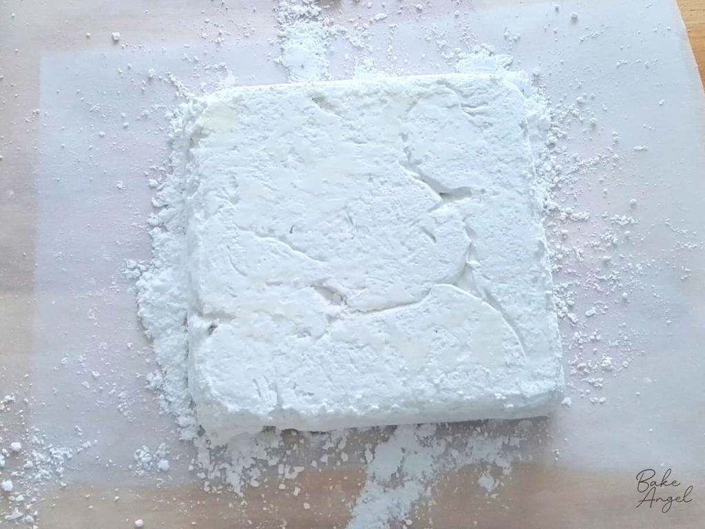 A set slab of marshmallow turned out onto parchment paper dusted with icing sugar.