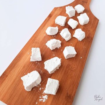 Small pieces of vanilla marshmallows on a wooden board.
