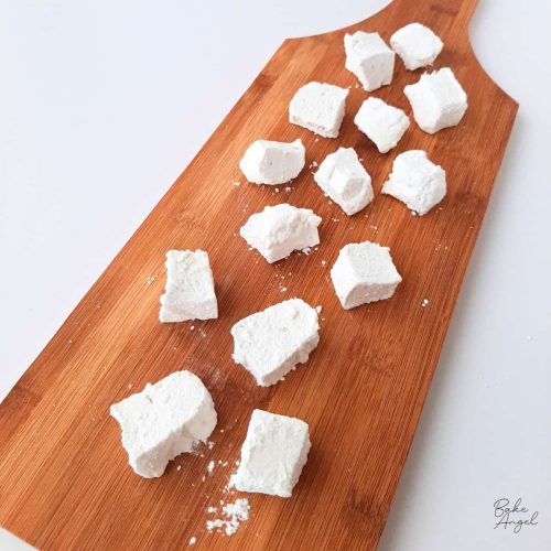 Small pieces of vanilla marshmallows on a wooden board.