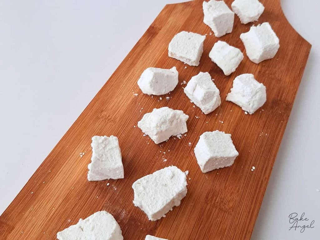 Small pieces of homemade marshmallows on a wooden board.