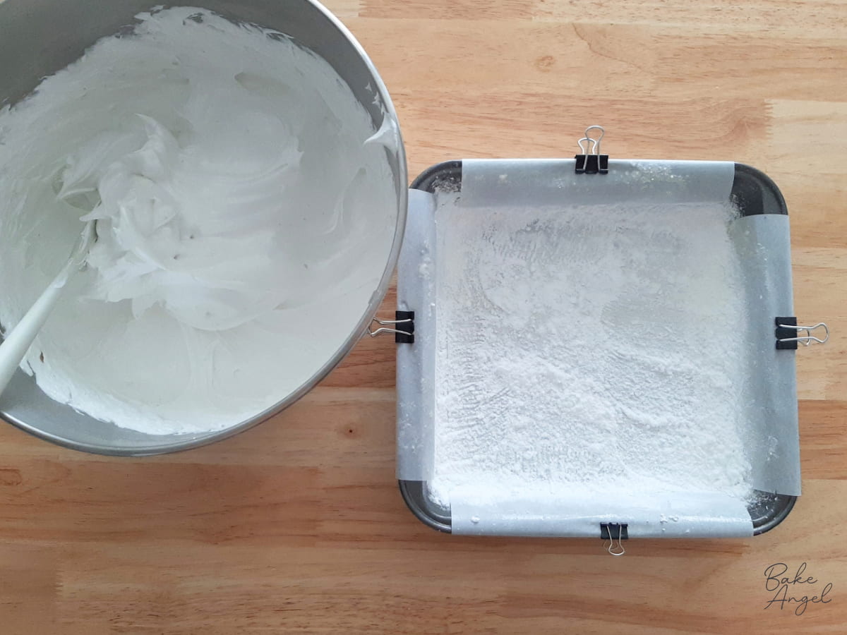 Marshmallow mixture in a bowl next to a prepared pan.