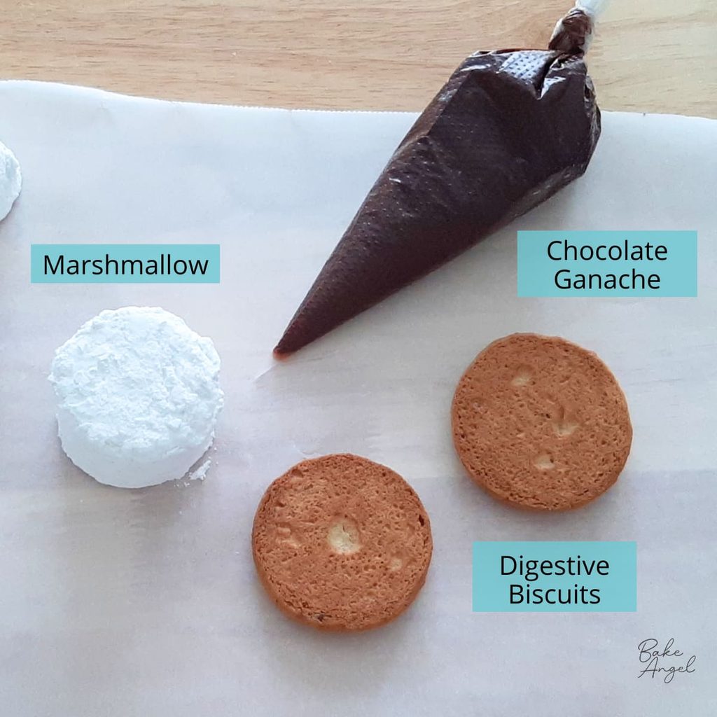 Ingredients to assemble homemade s'mores: marshmallow, two digestive biscuits, and a piping bag filled with chocolate ganache.